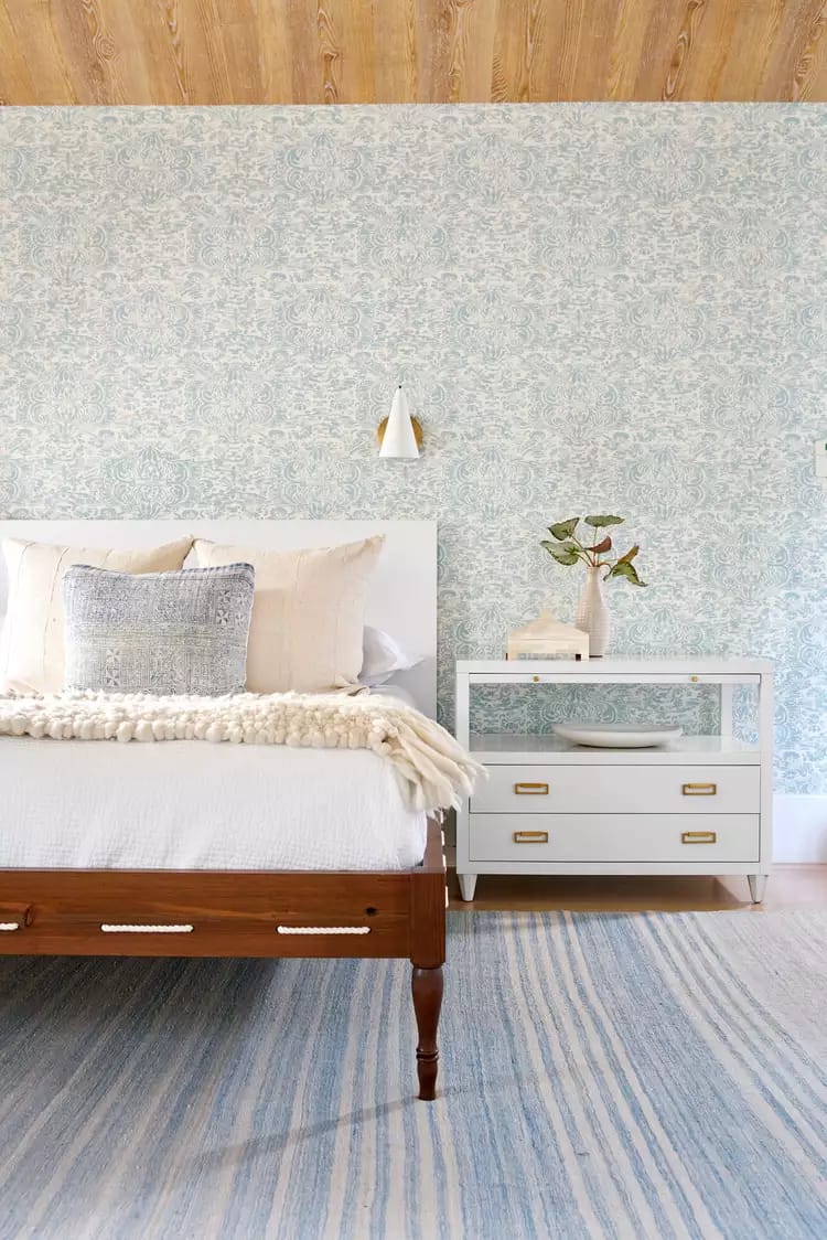 Interior kitchen with brick wall, wooden floor, white cabinets, and a lamp on tripod stand